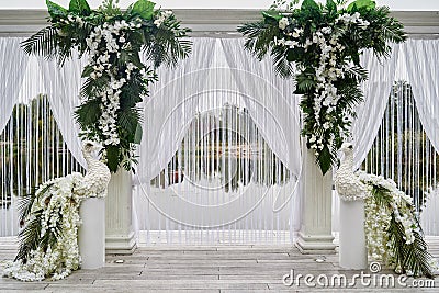 Luxury wedding arch decorated with palm leaves, orchid flowers and floral peacocks outdoors, copy space. Wedding ceremony. Stock Photo