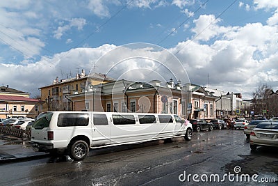 Luxury white limousine is waiting for the newlyweds in the alley on the background of the House of family celebrations after the Editorial Stock Photo