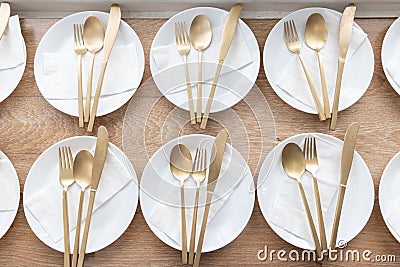 A luxury white plate, golden fork, spoon and knife with paper napkin on wooden table Stock Photo