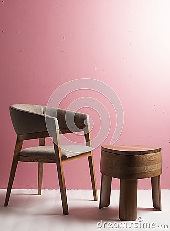 Luxury wooden chair with polished wooden table with three legs in a space with pink wall and cream floor with ambient light Stock Photo