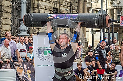 LVIV, UKRAINE - AUGUST 2017: A strong athlete picks up a huge heavy pack of barbell over his head in front of admiring spectators Editorial Stock Photo