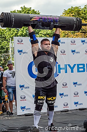 LVIV, UKRAINE - AUGUST 2017: A strong athlete picks up a huge heavy pack of barbell over his head in front of admiring spectators Editorial Stock Photo