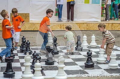 LVIV, UKRAINE - JUNE 2016: Young children, the future grandmasters play on a chess board chess exercising outdoors huge figures Editorial Stock Photo