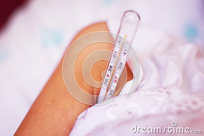 Lying sick woman with thermometer in the armpit . Woman measures body temperature under his arm with digital thermometer Stock Photo