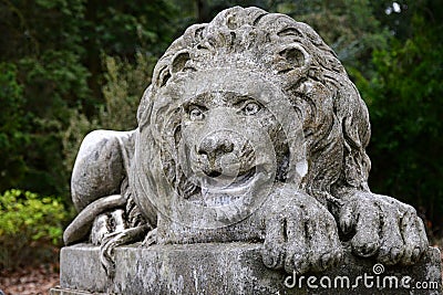 Lying stone lion statue, staring forward, placed on stone pedestal Stock Photo