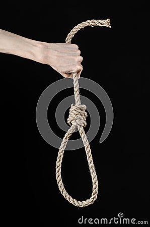 Lynching and suicide theme: man's hand holding a loop of rope for hanging on black isolated background Stock Photo