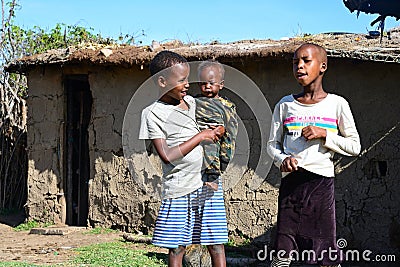 Maasai children walk in the courtyard near traditional adobe house Editorial Stock Photo