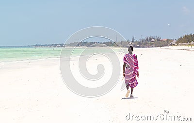 Maasai warrior walking on picture perfect tropical sandy beach. Paje, Zanzibar, Tanzania. Editorial Stock Photo