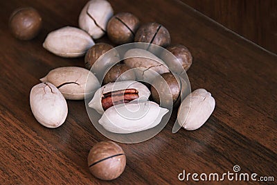 Macadamia, Brazil nuts, Bertholletia, pecan on brown wood background. roasted and notched exotic shell nuts background Stock Photo