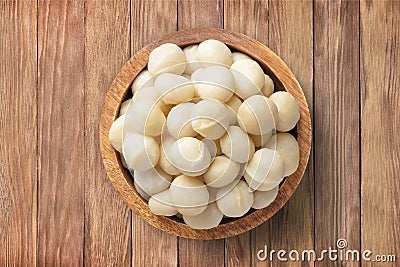 macadamia nuts peeled in bowl on wooden table background, top view. organic vegetarian food Stock Photo