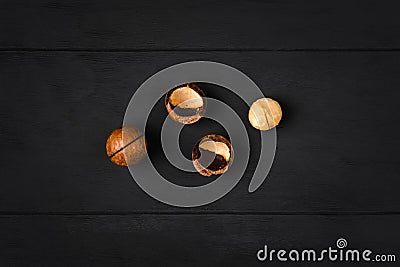 Macadamia nuts - peeled and unpeeled - on a dark wooden background Stock Photo