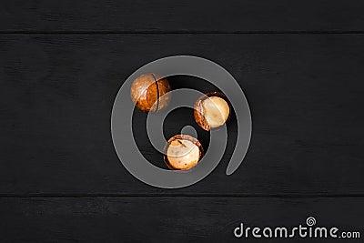 Macadamia nuts - peeled and unpeeled - on a dark wooden background Stock Photo