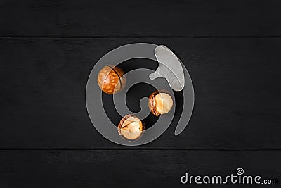 Macadamia nuts - peeled and unpeeled - and a special key on a dark wooden background Stock Photo