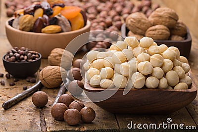 Macadamia nuts peeled in wooden bowl on table, grunge style. Stock Photo