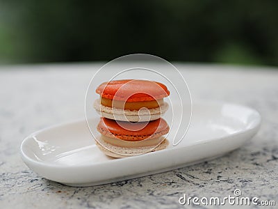 Macaron orange color in white plate shape ellipse, Dessert snacks Afternoon on marble table Stock Photo