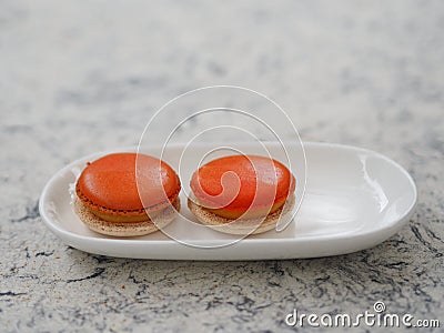 Macaron orange color in white plate shape ellipse, Dessert snacks Afternoon on marble table Stock Photo