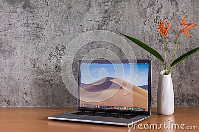 Macbook computers and flowers vase on wooden table Editorial Stock Photo