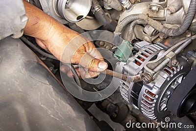 Machanic, worker hand-holding wrench repair car alternator in a garage. Repairing and maintenance automobile concept Stock Photo