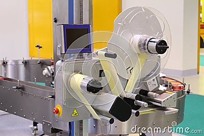 Machine for applying self-adhesive labels. The machine is designed for automatic labeling on a cylindrical container Stock Photo