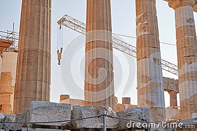 Machine crane between columns of Parthenon temple at the Acropolis, Athens, Greece, at sunset. Restoration process Stock Photo