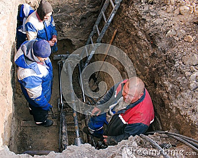Machine for installing sewerage. The workers are discussing a technical problem Editorial Stock Photo