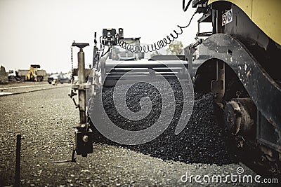 Machinery laying fresh asphalt or bitumen during road construction on building site. vintage, retro effect on photo Stock Photo