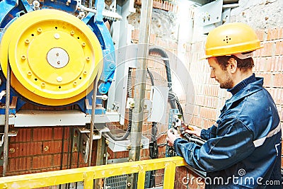 Machinist worker adjusting elevator mechanism of lift Stock Photo