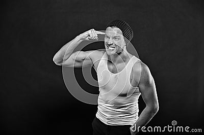 Macho with angry face. Man with finger at head. Athlete in fashion vest and hat with hand gesture. Anger and stress Stock Photo
