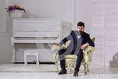 Macho attractive and elegant on serious, thoughtful face sitting on old fashioned armchair. Wealth and richness concept Stock Photo