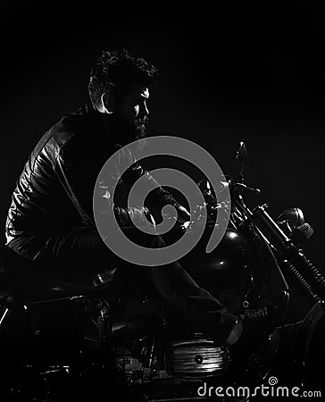 Macho, brutal biker in leather jacket riding motorcycle at night time, copy space. Man with beard, biker in leather Stock Photo