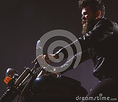 Macho, brutal biker in leather jacket riding motorcycle at night time, copy space. Masculinity concept. Man with beard Stock Photo