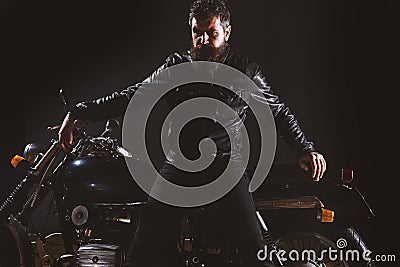 Macho, brutal biker in leather jacket stand near motorcycle at night time, copy space. Man with beard, biker in leather Stock Photo