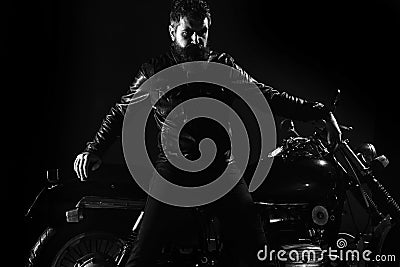 Macho, brutal biker in leather jacket stand near motorcycle at night time, copy space. Man with beard, biker in leather Stock Photo
