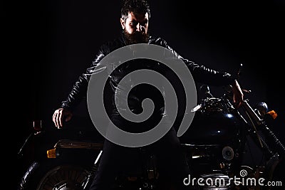 Macho, brutal biker in leather jacket stand near motorcycle at night time, copy space. Man with beard, biker in leather Stock Photo