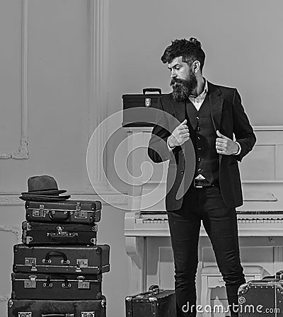 Macho stylish on thoughtful face standing near pile of vintage suitcase. Man, traveller with beard and mustache with Stock Photo