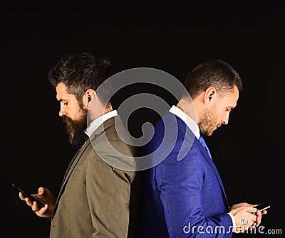 Machos in classic suits text on mobile phone. Stock Photo