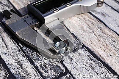 Macro close up of electronic digital calliper with nut between measuring jaws, lcd display and metric scale. Stones background Stock Photo