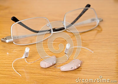 Close up of a pair of tiny modern hearing aid on bedside table Stock Photo