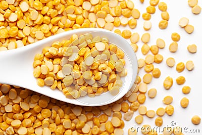 Macro Close-up of Organic Bengal Gram Cicer arietinum or split yellow chana dal on a white ceramic soup spoon. Top view, over Stock Photo