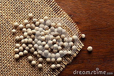 Macro close-up of Organic White peppercorns Piper nigrum on the wooden top background and jute mat. Pile of Indian Aromatic Spic Stock Photo