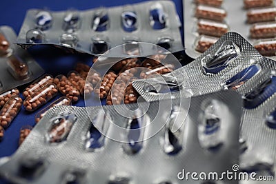 Macro close up of silver empty blisters with pile of capsules, blue background - medicines waste abuse concept Stock Photo