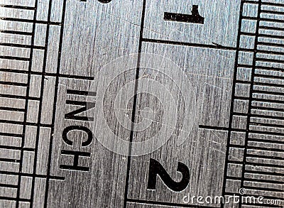 Macro close-up of a stainless steel ruler with british and metric system measuring scales. Stock Photo