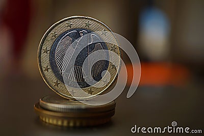 Macro detail of a metal Euro coin on the column created of coins with a positive warm background Stock Photo