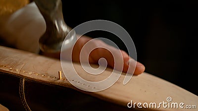 MACRO Unrecognizable shoemaker hammering together the sole of a custom made shoe Stock Photo