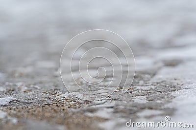 macro ground level closeup view of rock salt ice-melt on concrete with a frozen layer. Stock Photo
