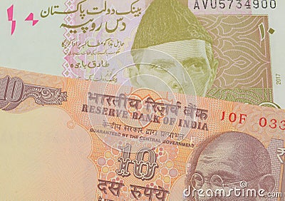 A orange ten rupee bill from India paired with a pink and grey ten rupee note from Pakistan. Stock Photo