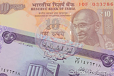 A orange ten rupee bill from India paired with a purple fifty dinar bill from Iraq. Stock Photo