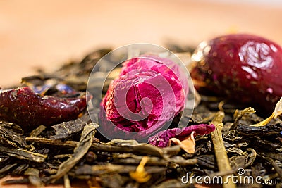 Macro photo of tea with a tea rose. The composition of the heap of tea roses and dried hibiscus flower located on a wooden Board. Stock Photo