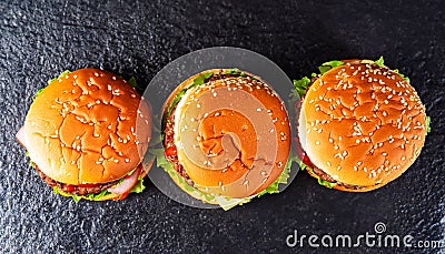 macro photo of three hamburgers_on black kitchen granite surface top view Stock Photo