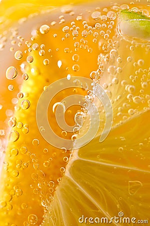 Macro photo of yellow lemon slices with lots of bubbles in a glass with water. Summer cold lemonade Stock Photo